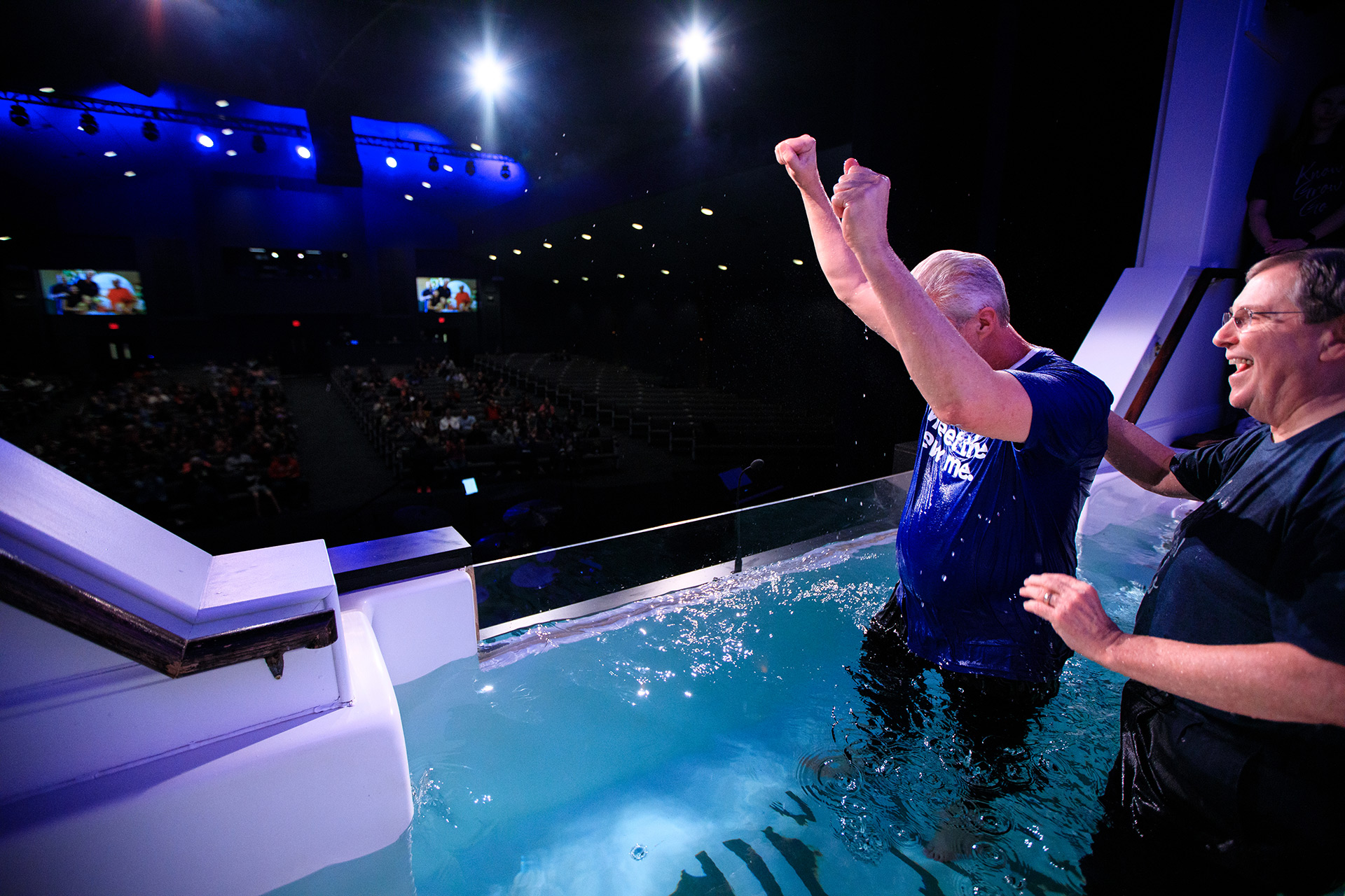 A man raising his hands in celebration after being baptized