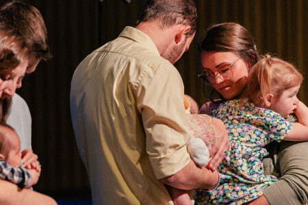 Family praying together at Baby Dedication