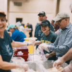 Group laughing as they pack meals together.