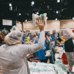 Group celebrating a completed box of packed meals.